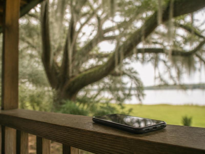 Phone on a porch rail under live oaks